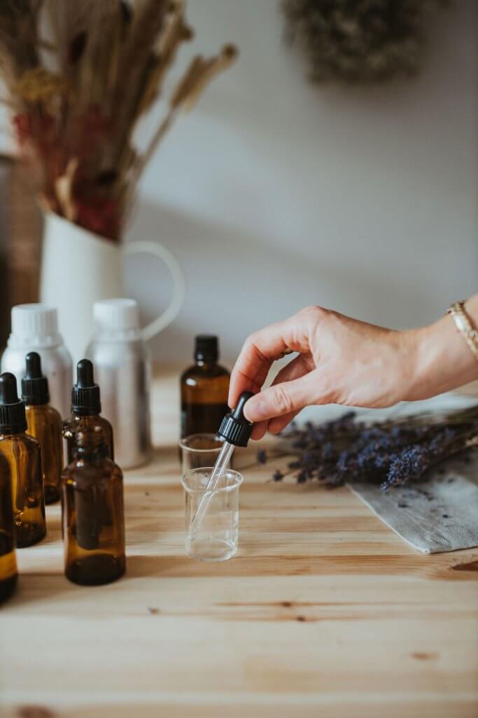 A woman measuring essential oils in a dropper