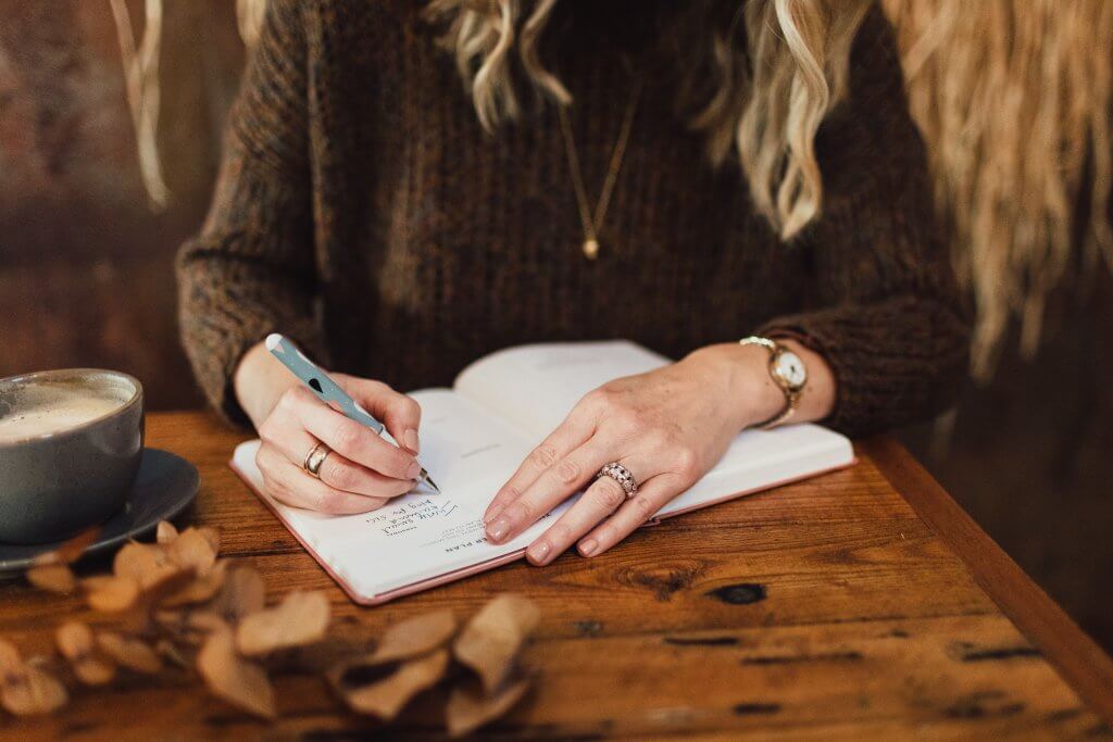 A woman writing a winter wellness list.