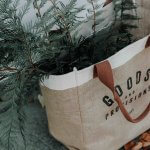 A picture of a woven shopping bag filled with pine branches. Image from Unsplash.
